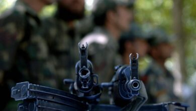 Indian soldiers stand beside a display of AK47 assault rifles