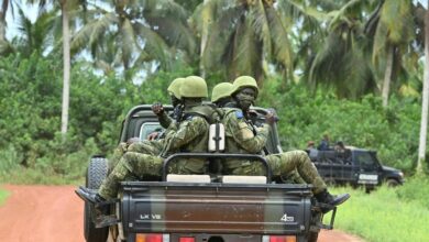 Ivorian soldiers drive on the back of a vehicle outside the International Academy for Combating Terrorism in Jacqueville in Ivory Coast on June 10, 2021