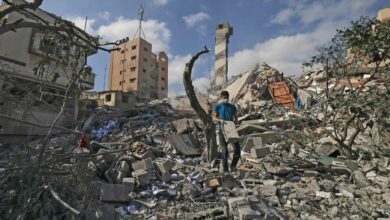 A Palestinian youth looks for salvageable items amid the rubble of the Kuhail building, which was destroyed in an early morning Israeli airstrike on Gaza City
