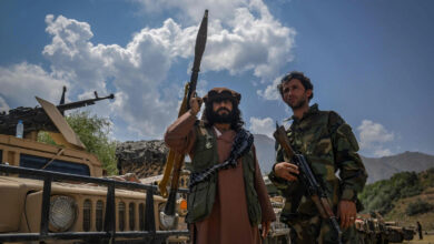 Afghan armed men supporting the Afghan security forces against the Taliban stand with their weapons and Humvee vehicles in Panjshir province