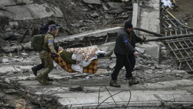 Ukrainian servicemen evacuate an elderly woman