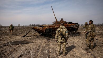 Ukrainian soldiers stand by a burnt Russian tank on the outskirts of Kyiv, on 31 March, 2022