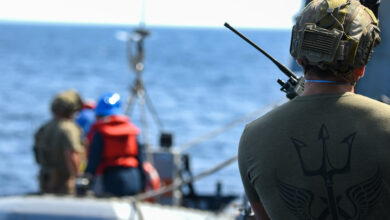 210830-N-UP745-1104 ATLANTIC OCEAN (Aug. 30, 2021) U.S. Coast Guardsman uses a two-way radio to direct a rigid-hulled-inflatable boat during a small-boat operation aboard the USS Forrest Sherman (DDG 98). Forrest Sherman is conducting Initial Ship Aviation Team Training with HSM-60 Detachment 2 in the Virginia Capes. (U.S. Navy Photo by Mass Communication Specialist Seaman Theoplis Stewart II/Released)