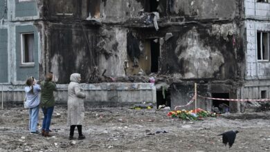 People pay their respects in front of a damaged multistory residential building