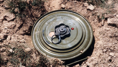 A Russian tank mine is seen on the ground. It is surrounded by dirt, seemingly before being buried.