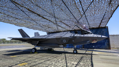 An F-35A Lightning II aircraft under a temporary aircraft revetment being trialled at RAAF Base Williamtown, New South Wales. *** Local Caption *** In October 2023, the Air Combat Group initiated and executed a trial to construct a temporary aircraft revetment at RAAF Base Williamtown. The trial demonstrated alternative passive defence methods and materials. Aircraft revetments are open-air structures intended to shield parked aircraft from discovery, blast and fragmentation damage. Personnel from No.65 Air Base Recovery Squadron were tasked with constructing the revetment. The trial aimed to inform Air Force of future dispersed aircraft revetment solutions in support of agile operation concepts.