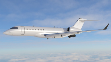 A white Bombardier Global 6500 airplane is seen flying among the clouds. The blue sky serves as the background.