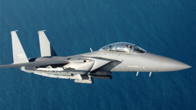 A Republic of Korea Air Force F-15K fighter plane is seen flying above a body of water. The fighter plane is painted gray and has a sleek body to make it more aerodynamic. The number "013" is painted on its tail in white.