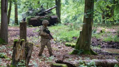 UK soldier patrolling the immediate area surrounding a command post, with a KRH Challenger 2 and its crew waiting nearby
