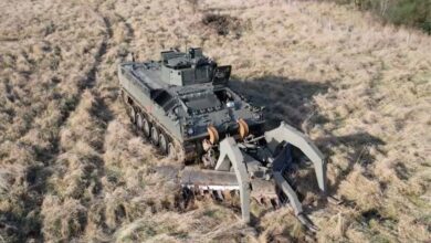 The remote-controlled robotic mine plough system "Weevil" attached to a military vehicle moving through a field