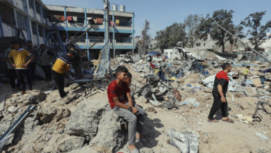 People walk through rubble and debris outside Abu Hamisa School in Al-Bureij camp, Gaza, on May 10, 2025. The school, used as a shelter for displaced families, was bombed twice on the same day several days ago. (Photo by Moiz Salhi / Middle East Images / Middle East Images via AFP)