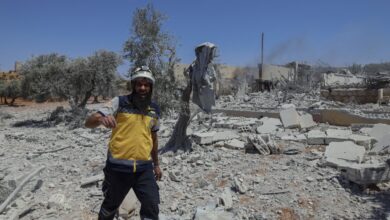 A rescue worker walking over the rubble of a destroyed building in Syria