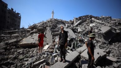 Palestinians walking over rubble of fallen building in Gaza