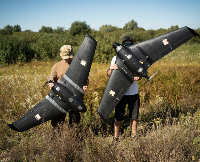 Two people show off the new kamikaze drones developed by Brave1 for Ukraine forces