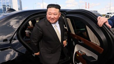 North Korean leader Kim Jon Un exiting a black limousine while wearing a black suit