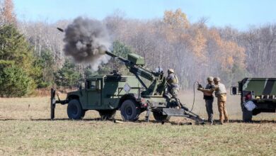 Soldiers firing a HUMVEE Hawkeye 105-millimeter soft recoil mobile howitzer