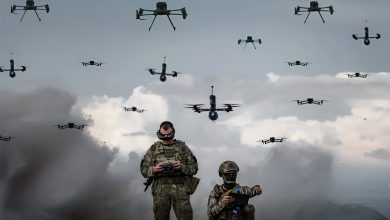 Two Ukrainian soldiers stand proudly in front of a lineup of military drones, showcasing their advanced technology.