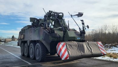 A Black Hornet nano drone hovering in front of a Piranha armored engineering vehicle