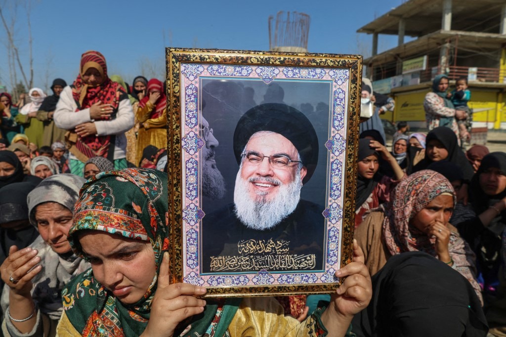 A Shiite Muslim woman holds a portrait of the late leader of the Lebanese group Hezbollah, Hassan Nasrallah, during a protest against the killing of Iran's Supreme Leader Ayatollah Ali Khamenei in Shadipora, Sumbal area of Bandipora District, north of Srinagar, Jammu and Kashmir, on March 3, 2026.
