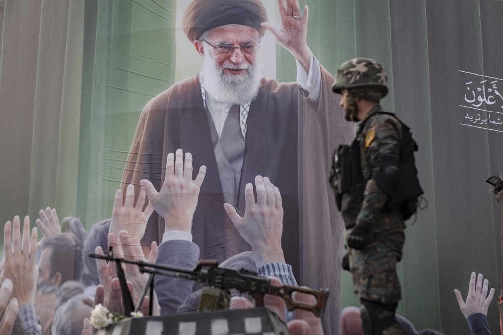 An armed Iranian policeman monitors an area while standing on an armored vehicle in front of a portrait of Iran's late Supreme Leader Ayatollah Ali Khamenei, who is killed in a U.S.-Israeli military campaign in Tehran, Iran, on March 7, 2026.