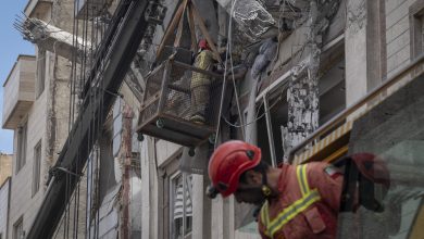 Iranian firefighters work to recover the body of an Afghan woman from the ruins of a residential building in Tehran, Iran, on March 27, 2026.