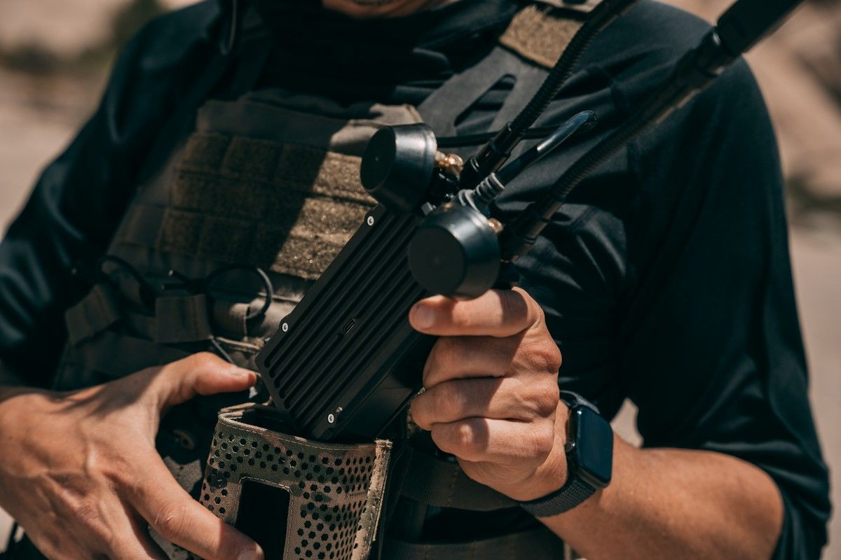 Soldier in tactical vest holding Neros Crossbow Block 2 wearable drone control station with multi-antenna array