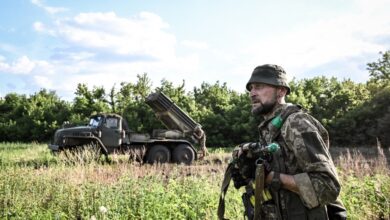 A soldier from the 148th Separate Artillery Zhytomyr Brigade of the Ukrainian Airborne Forces stands guard as servicemen prepare to fire missiles from a BM-21 Grad multiple launch rocket system at Russian positions in the Oleksandrivka sector, Dnipropetrovsk region, Ukraine, on June 22, 2026. (Photo by Dmytro Smolienko/Ukrinform/NurPhoto via AFP)