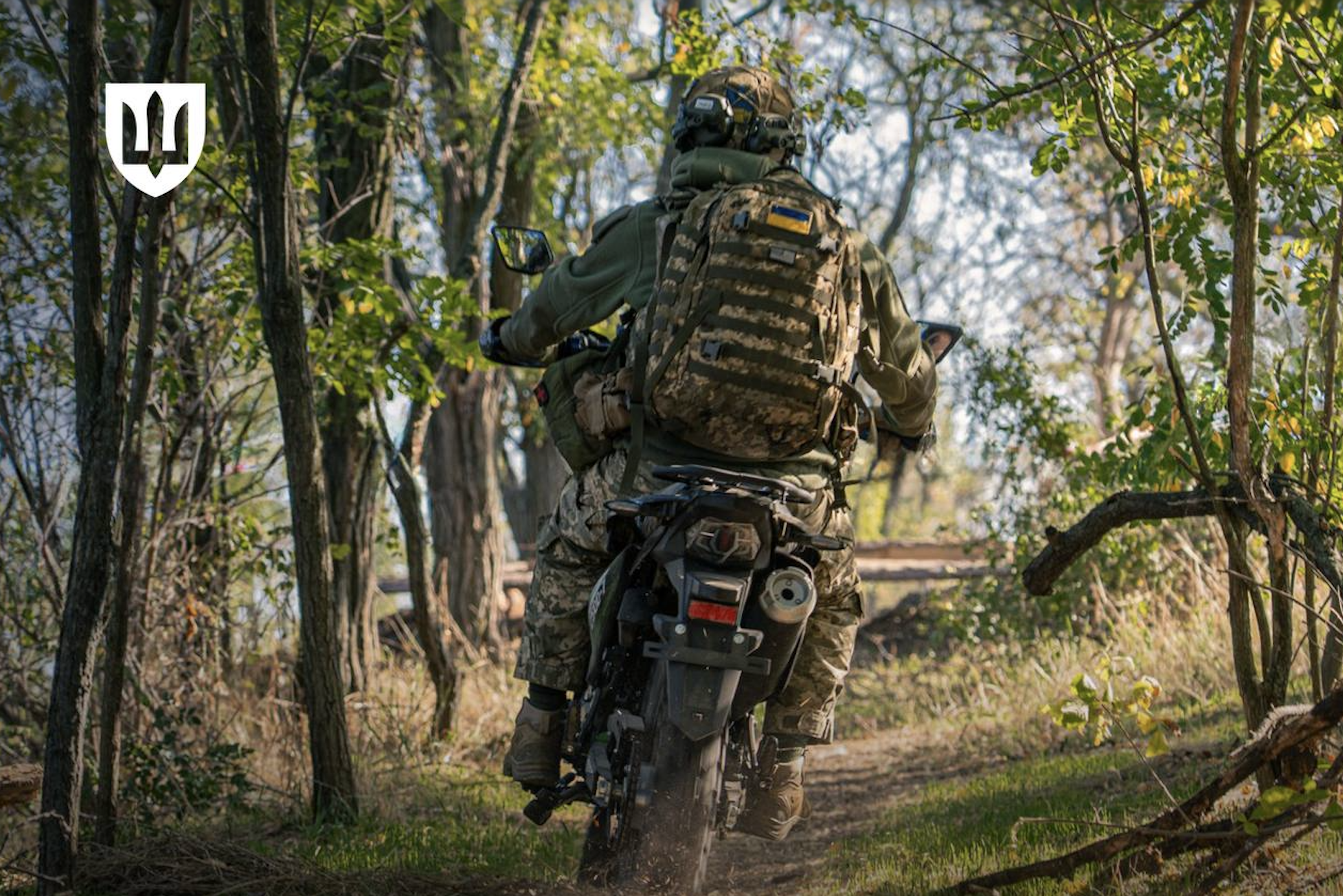 Ukraine soldiers ride a motorcycle.